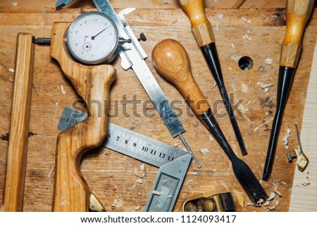 Tools on the desktop in the workshop. Making a violin. Wood shavings and dust, creative mess. Thickness gauge, chisel, cutter, blade, plane.