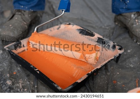 Tools for the painter and redecoration. Close-up of orange paint and roller brush in the tray. Close-up [[stock_photo]] © 