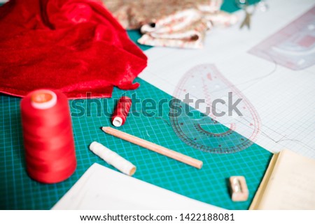 Tools, patterns and fabric samples on the sewing table in the tailor workshop