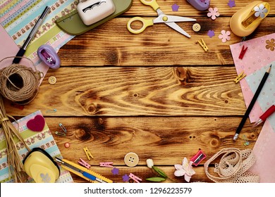 Tools for scrapbooking on the wooden background. Copy space in the middle.