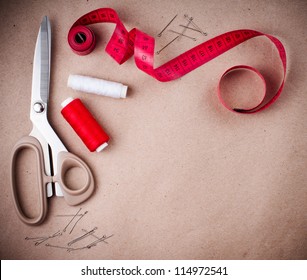 Tools for sewing and handmade: thread, scissors, pins on brown paper. - Powered by Shutterstock