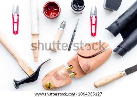 Tools for shoe repair. Hummer, awl, knife, sciccors, wooden shoe, insole, paint and leather. White background top view pattern