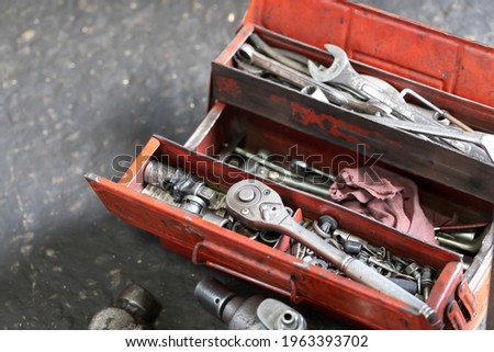 tools in steel box. red open tool box on dirty garage floor.