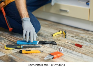 Tools To Succeed. Close Up Of Hand Of Repairman, Professional Plumber Choosing The Best Tool For Fixing A Sink. Tools And Equipment On The Floor In The Kitchen