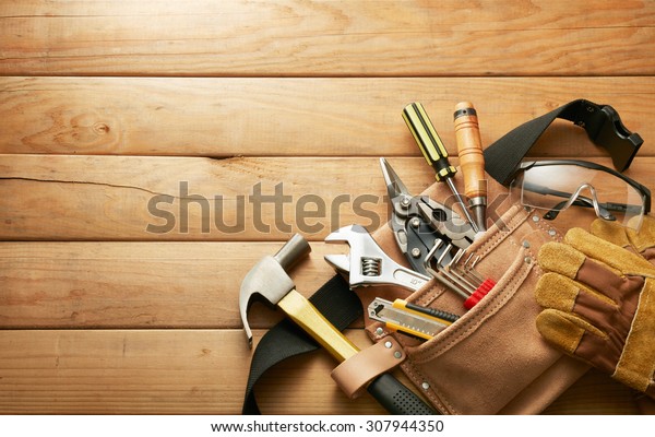 tools in tool\
belt on wood planks with copy\
space