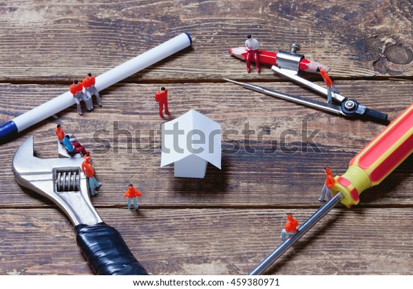tools, toy people and paper model house on a\
wooden surface.view from\
above\
