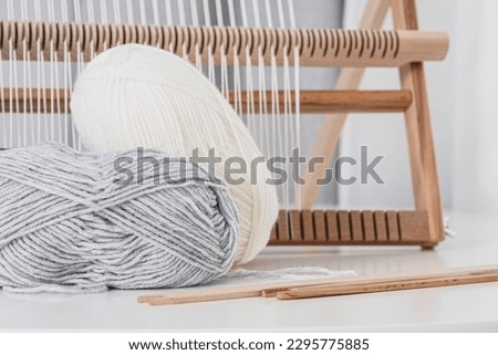 Tools for weaving tapestries. Wooden weaving frame and yarn on a table on a white background. Warp thread stretched over a weaving frame. The ancient art of weaving cloth.