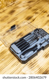 Toolset with multiple screwdrivers and bits inside a clear case, positioned on a wooden surface showcasing natural grain and texture