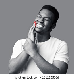 Tooth Pain And Dentistry. African Man Suffering From Terrible Toothache, Touching Cheek With Hand, Black And White Image