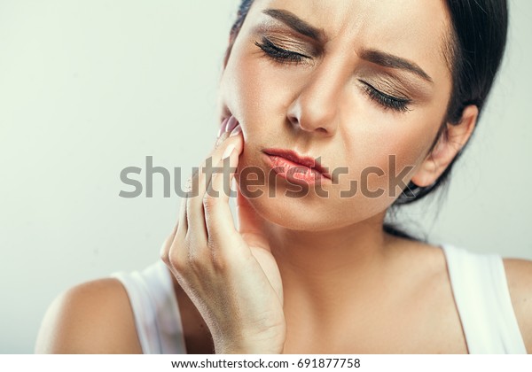 Tooth Pain And Dentistry. Beautiful Young\
Woman Suffering From Terrible Strong Teeth Pain, Touching Cheek\
With Hand. Female Feeling Painful Toothache. Dental Care And Health\
Concept. High Resolution