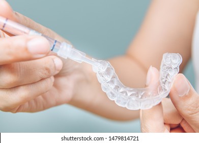 Tooth whitening gel being applied to a tooth mold in preparation for being placed in the mouth. - Shutterstock ID 1479814721