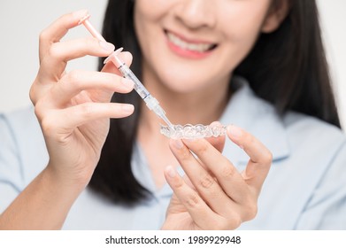 Tooth whitening gel being applied to a tooth mold in preparation for being placed in the mouth. - Shutterstock ID 1989929948