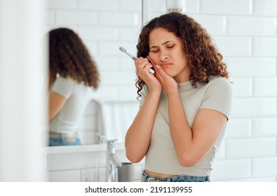 Toothache, pain and sensitive teeth with a woman brushing her teeth in a bathroom at home. Young female with a cavity suffering from discomfort during dental hygiene routine. Lady with a sore mouth - Shutterstock ID 2191139955