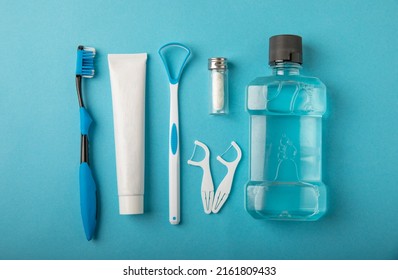 Toothbrush, tongue cleaner, floss, toothpaste tube and mouthwash on blue background with copy space. Flat lay. Dental hygiene. Oral care kit. Dentist concept. - Shutterstock ID 2161809433