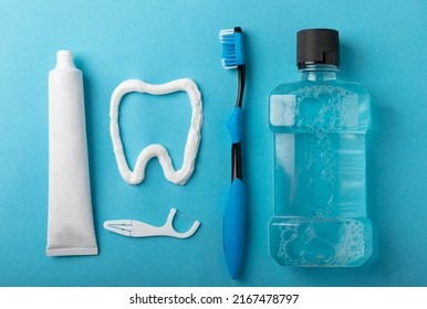 Toothbrush, tongue cleaner, floss, toothpaste tube and mouthwash on blue background with copy space. Flat lay. Dental hygiene. Oral care kit. Dentist concept. - Shutterstock ID 2167478797