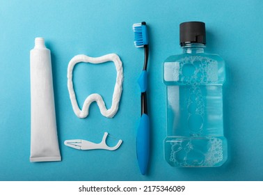 Toothbrush, tongue cleaner, floss, toothpaste tube and mouthwash on blue background with copy space. Flat lay. Dental hygiene. Oral care kit. Dentist concept. - Shutterstock ID 2175346089