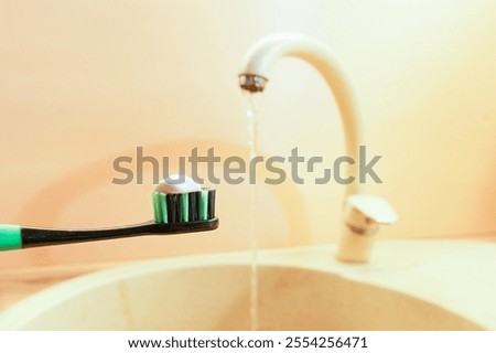 Toothbrush with toothpaste against the background of a tap with running water. Concept of personal hygiene and  healthy lifestyle.                               