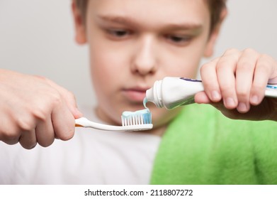 Toothbrush and toothpaste in the hands of a boy. The process of squeezing the paste from the tube - Powered by Shutterstock