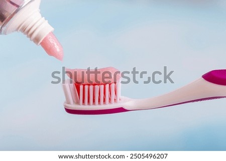 Toothbrush with toothpaste on blue background. Applying toothpaste on brush against blurred background. Means to care for the oral cavity.
