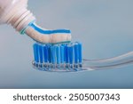 Toothbrush and toothpaste, Squeezing toothpaste onto toothbrush. Applying toothpaste on brush against blurred background, closeup.