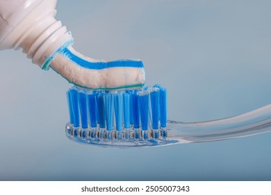 Toothbrush and toothpaste, Squeezing toothpaste onto toothbrush. Applying toothpaste on brush against blurred background, closeup.