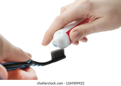 A Toothbrush And Tube Of Toothpaste In A Hand Isolated On White Background, Squeezing Toothpaste On The Toothbrush