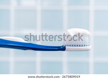 Toothbrush with white toothpaste close up on blue tile background.