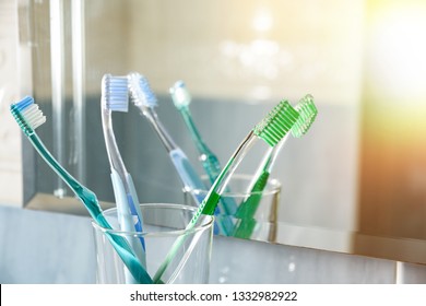 Zahnbürsten in einer Glasvase in einem blauen Badezimmer vor einem Spiegel. Horizontale Zusammensetzung. Vorderseite.