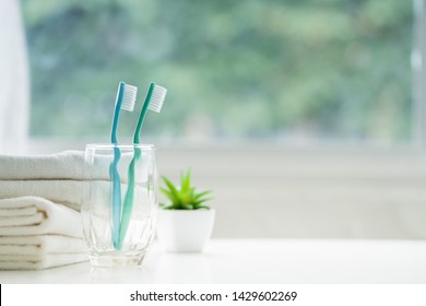 The toothbrushes in a glass and white towels with copy space in bathroom 