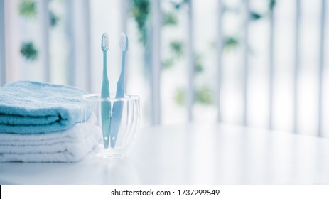 Die Zahnbürsten in einem Glas und weiße Handtücher mit Kopierraum im Badezimmer 