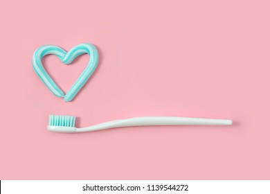 Toothbrushes and turquoise color toothpaste in shape of heart on pink background. Dental and healthcare concept. - Powered by Shutterstock