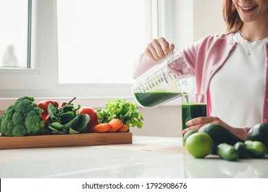 Toothily smiling red haired girl with freckles putting some vegetable juice in the glass