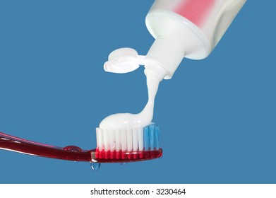 Toothpaste being applied to a red toothbrush