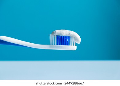 Toothpaste on a toothbrush close-up on a cyan-white background 