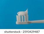 Toothpaste squeezed on the white toothbrush on blue background, close up. Dental care and hygiene tooth concept