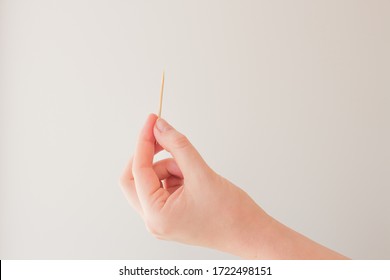 Toothpick in female hand on white background. The concept of dental hygiene, oral health. Card with copy space for text