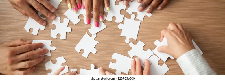 Top above close up hands diverse team assembling jigsaw puzzle joining pieces at desk search right solution, successful teamwork help support concept, horizontal photo banner for website header design