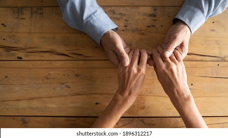 Top Above Close Up View Compassionate Middle Aged Man Holding Wrinkled Hands Of Elderly Woman, Copy Space. Loving Old Mature Married Retired Couple Showing Care, Supportive Family Relations Concept.