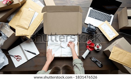 Top above closeup view of female online store small business owner entrepreneur packing package post shipping box preparing delivery parcel on table. Ecommerce dropshipping shipment service concept.