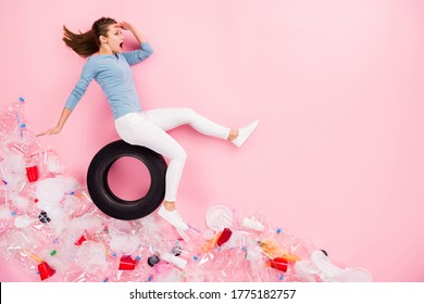 Top above high angle view full length profile side photo activist volunteer girl sit automobile tyre ride down plastic trash hand see copyspace flat lay isolated pastel color background