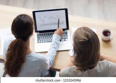 Top Above Rear View Businesswoman Sitting Together At Office Desk Working Using Computer Business Software Application. Colleague Helps Intern Understand Corporate Program Analyzing Data And Graphic