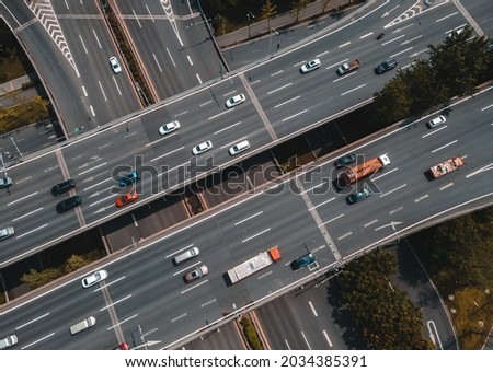 Top up aerial drone view of elevated road and traffic junctions in Chinese metropolis city during sunny day golden hour. Modern construction design of traffic ways to avoid traffic jams. Few vehicles.