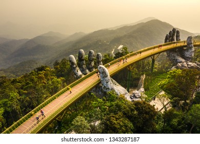 Top aerial view of the famous Golden Bridge is lifted by two giant hands in the tourist resort on Ba Na Hill in Da Nang, Vietnam. " Cau Vang" is a favorite destination for tourists

