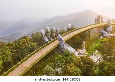 Top aerial view of the famous Golden Bridge is lifted by two giant hands in the tourist resort on Ba Na Hill in Da Nang, Vietnam. " Cau Vang" is a favorite destination for tourists