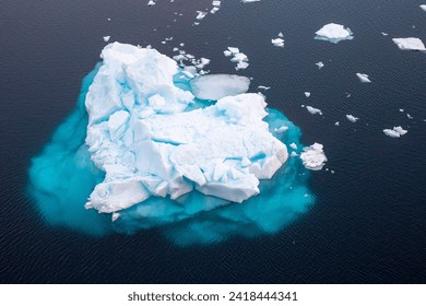 Top or aerial view of a huge iceberg floating in the dark blue sea in Antartica  - Powered by Shutterstock