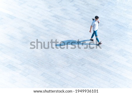 top aerial view man people with face mask walk on across pedestrian concrete with black silhouette shadow on ground, concept of social new normal life prevention of covid pandemic and air pollution.