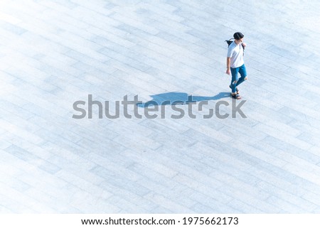 top aerial view man people with face mask walk on across pedestrian concrete with black silhouette shadow on ground, concept of social new normal life prevention of covid pandemic and air pollution.
