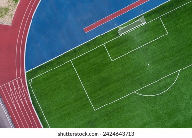 Top aerial view of opened stadium - cropped football field with a goal and red tracks - Powered by Shutterstock