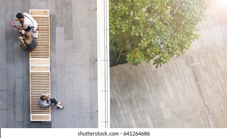 Top Aerial View Of People Sit On Wood Bench At The Upper Floor Pedestrian With The Lower Floor Of Tree Garden And Street.