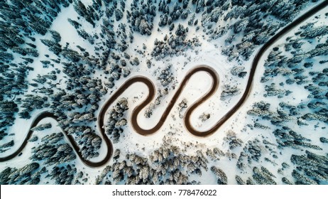 Top aerial view of snow mountain landscape with trees and road. Dolomites, Italy.